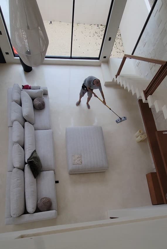 Overhead view of a Qtana cleaner mopping a bright, two-story living room in a Playa del Carmen rental